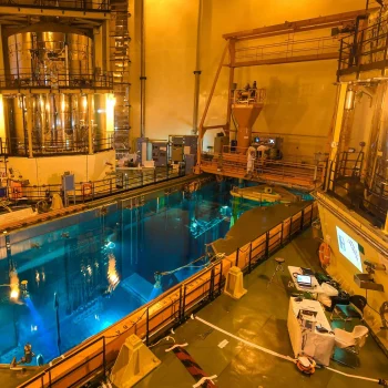 Refueling bridge above a blue spent fuel pool inside a nuclear facility.
