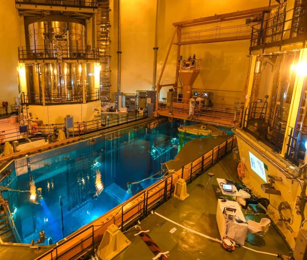 Refueling bridge above a blue spent fuel pool inside a nuclear facility.